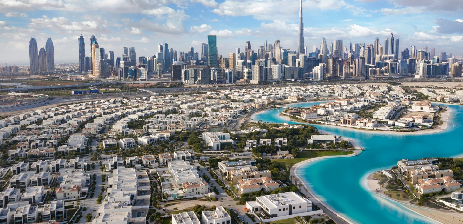 Aerial view of a Dubai residential community with the city skyline and Burj Khalifa behind